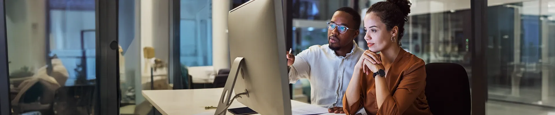 Image of man and woman working together at computer in corporate business environment