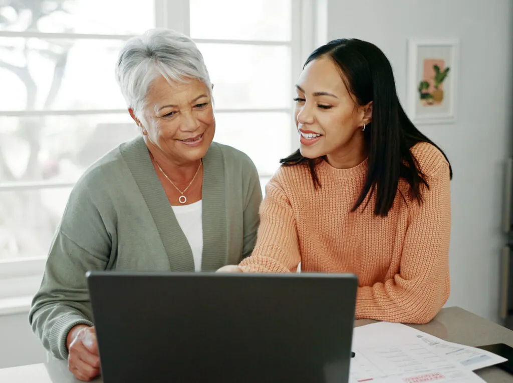 Mother and daughter navigate online web portal for account management of services