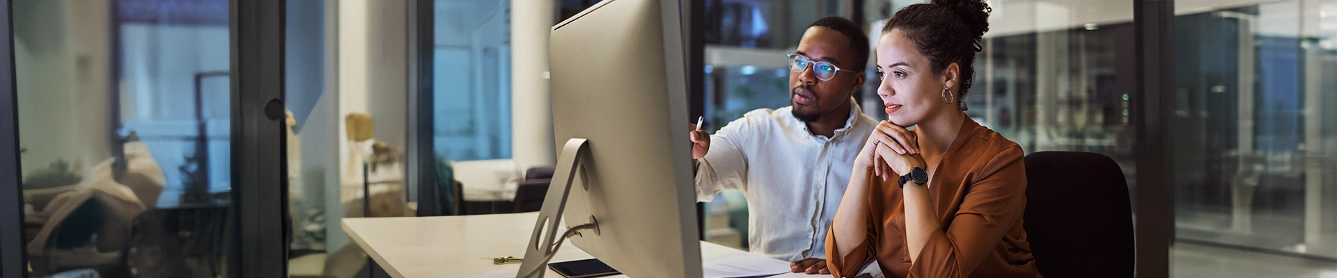 Image of man and woman working together at computer in corporate business environment
