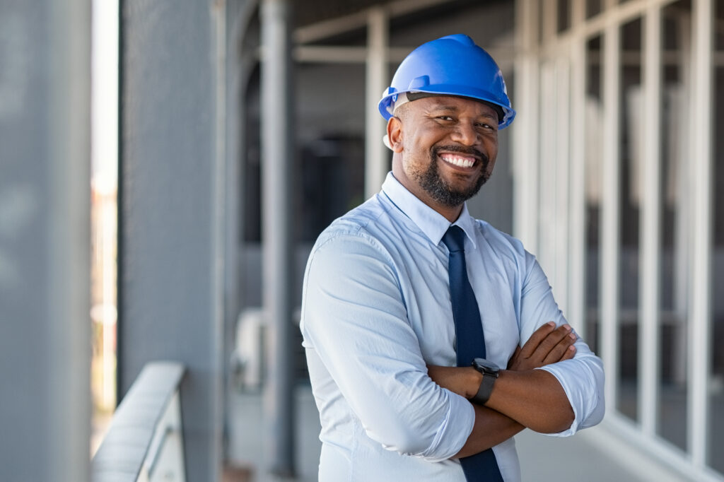 Image of confident man at contractor build site wearing hardhat